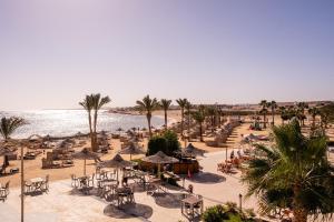 a beach with chairs and umbrellas and the ocean at Shoni Bay Resort in Marsa Alam City