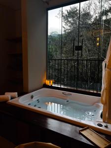 a bath tub in a room with a large window at Shoresh Araucária in Campos do Jordão