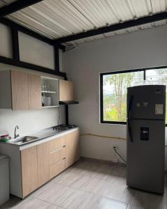 a kitchen with a refrigerator and a window at Refugio raices in Guarne
