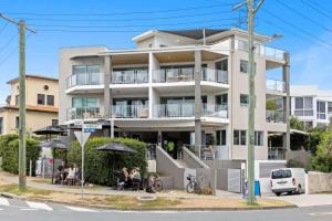 a white building with people sitting outside of it at Point Cartwright Penthouse - Ocean and River Views in Buddina