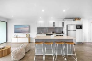a kitchen with a island and stools in a room at Point Cartwright Penthouse - Ocean and River Views in Buddina
