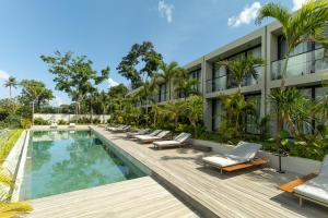 an exterior view of a hotel with a pool and lounge chairs at Ecoverse Resort & Residence by OXO - Nyanyi Beach, Bali in Cemagi