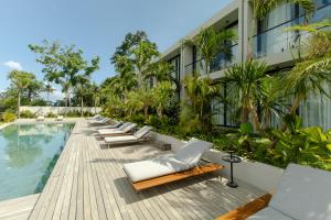 a row of lounge chairs next to a building with a pool at Ecoverse Resort & Residence by OXO - Nyanyi Beach, Bali in Cemagi