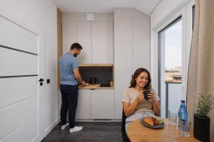 a woman sitting at a table in a kitchen at Apartamenty Racławicka Mszczonów in Mszczonów