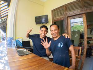 two men sitting at a table with their hands up at Blue Marlin Dive Resort Trawangan in Gili Trawangan
