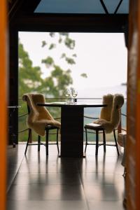 a glass table with two chairs and wine glasses on it at Caramelo Chalé in Rio do Sul +1 photo