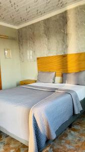 a bedroom with a large bed with a wooden headboard at Mukomani Guesthouse in Soshanguve