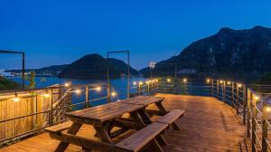 a wooden picnic table on a deck with a view of the water at Chuncheon Rabbit Star Pension in Chuncheon
