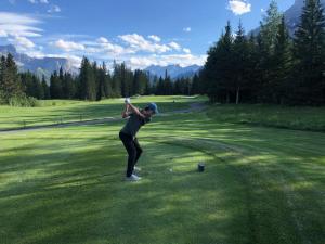 a woman swinging a golf club on a golf course at Merlot House in Calgary