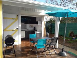 a patio with a table and chairs and an umbrella at Bungalow chic à Sainte-Rose + piscine. in Sainte-Rose