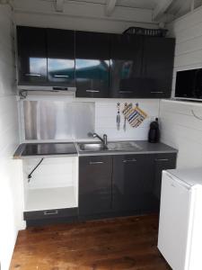a kitchen with black and white cabinets and a sink at Bungalow chic à Sainte-Rose + piscine. in Sainte-Rose