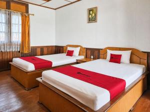 a room with two beds with red pillows at RedDoorz at Derawan Beach Cottage in Derawan Islands