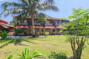a building with a palm tree in front of a yard at RedDoorz at Derawan Beach Cottage in Derawan Islands