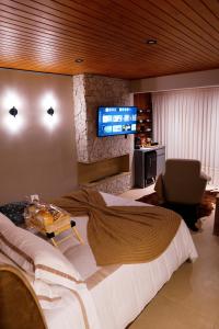 a bedroom with a large bed and a flat screen tv at Moldavite Bungalow in Treze Tílias