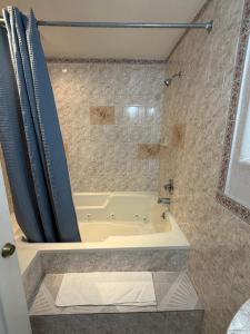 a bathroom with a tub and a shower with a shower curtain at Penguin Motel in Harbor City