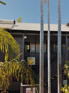 a building with palm trees in front of it at Roebuck Bay Backpackers in Broome