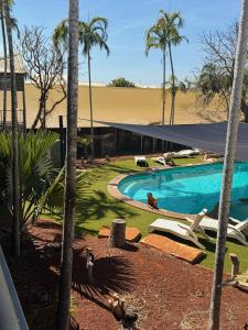 a swimming pool with palm trees and a building at Roebuck Bay Backpackers in Broome