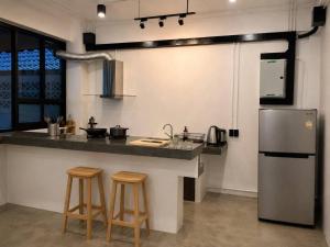 a kitchen with a counter with stools and a refrigerator at 9 mins to BTS Queen Private Room Share Bath in Amphoe Phra Khanong