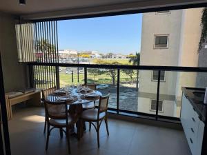 a dining room with a table and chairs and a large window at Loft Elegante proximo do Shopping Esmeralda in Marília