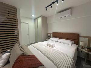 a bedroom with a large white bed and a couch at Loft Elegante proximo do Shopping Esmeralda in Marília