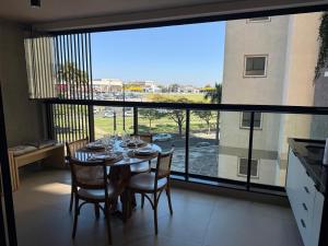 a dining room with a table and chairs and a large window at Loft Elegante proximo do Shopping Esmeralda in Marília