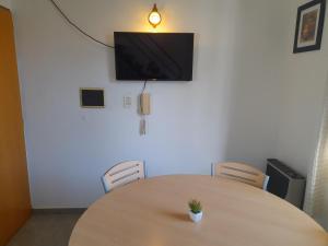 a wooden table with chairs and a tv on a wall at Neyen in La Plata