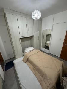 a bedroom with a large bed and a chandelier at Studio Brooklyn - 3 minutos da EPCAR in Barbacena +11 photos
