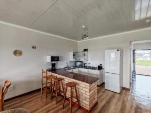 a kitchen with white appliances and a counter with stools at Princess Vlei Lodge in Grassy Park