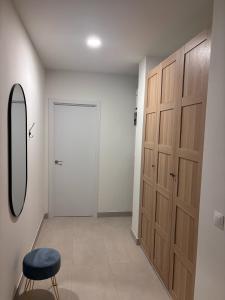 a hallway with wooden cabinets and a stool and a mirror at APARTAMENTO LEPANTO in Almazora