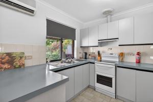 a white kitchen with white appliances and a window at Cockles on Willmett road in Goolwa