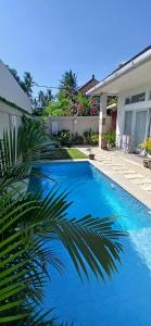 a blue swimming pool in front of a house at Villa Segara Agung Amed in Amed
