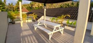 a wooden bench sitting on a patio with an umbrella at Villa Segara Agung Amed in Amed