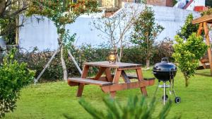 a picnic table and a grill in a garden at Jeju DK House Pension in Seogwipo