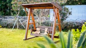 two stuffed animals sitting on a swing in a yard at Jeju DK House Pension in Seogwipo +2 photos