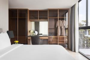 a bedroom with a large white bed and a desk at Walton Suites Sukhumvit in Bangkok