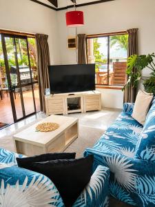 a living room with blue couches and a flat screen tv at Sunset Palms Rarotonga in Rarotonga