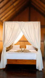 a bed with a canopy with white sheets and pillows at Puri Sunset Homestay in Munduk