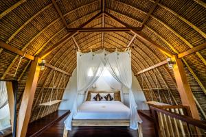 a bed in a thatched room with a window at Bunga Laut Bungalow in Amed