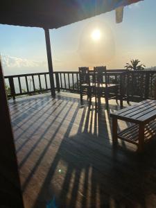 a deck with a table and chairs and the sun at Puri Sunset Homestay in Munduk