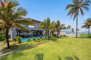 an exterior view of a house with palm trees at The Five Stars Villa 6 Bedrooms Beachfront in Danang