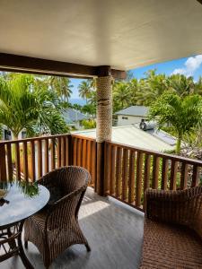 a balcony with a table and chairs and palm trees at Sunset Palms Rarotonga in Rarotonga