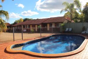 a swimming pool in front of a house at Childers Gateway Motor Inn in Childers