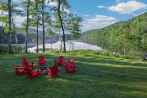 a group of red chairs sitting on the grass near a lake at Berkshire Lake Lodge in Becket +28 photos