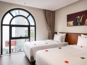 two beds in a hotel room with a window at La Passion Elegance Hotel & Spa in Hanoi +57 photos