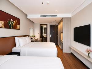 two beds in a hotel room with a flat screen tv at La Passion Elegance Hotel & Spa in Hanoi