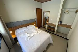 a bedroom with a white bed and a mirror at Vila dos Poetas in Barreirinhas