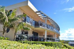 a house with a balcony and palm trees at Northpoint Apartment 5 - Bring your own linen. in South West Rocks