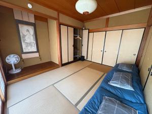 a small room with a bed and a fan at Yamaneko Lodge in Gujo