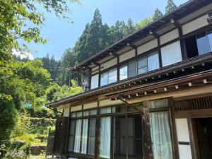 a building with windows and trees in the background at Yamaneko Lodge in Gujo