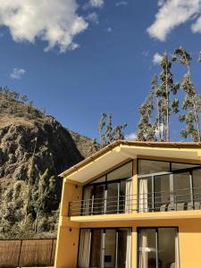 a yellow house with a mountain in the background at Earth Tones Tiny Homes & Suites in Ollantaytambo